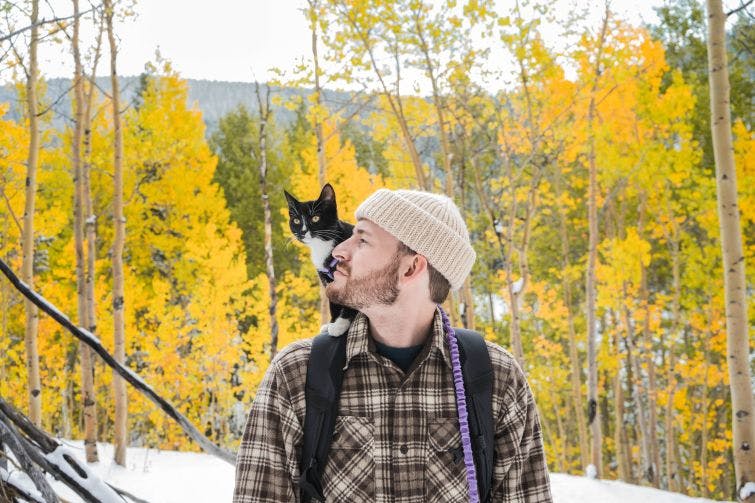 a man with a backpack and a cat on his shoulder