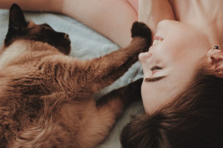a woman laying on a bed next to a cat