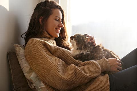 a woman sitting on a couch holding a cat