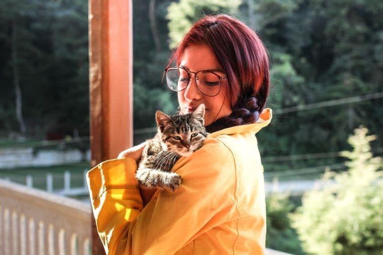 a woman in a yellow jacket holding a cat