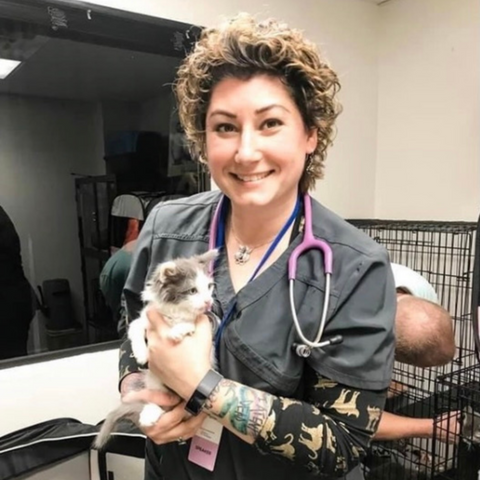 a woman in scrubs holding a cat in a cage